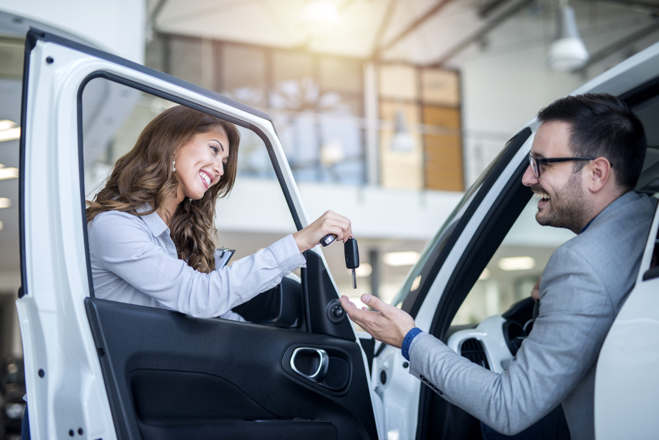 Car dealer and customer at vehicle showroom choosing new car.